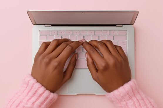 SEO pagina optimalisatie Een roze achtergrond, een roze toetsenbord en een roze trui - op de foto zie je iemand typen achter een laptop. Deze afbeelding wordt gebruikt voor de blog van Keller SEO over pagina optimalisatie.